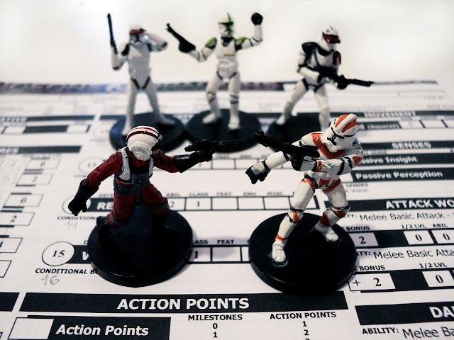 Cinco miniaturas de soldados de Star Wars, tres soldados imperiales de fondo que observan a un piloto rebelde enfrentándose a otro imperial, sobre una hoja de personaje de juego de rol.