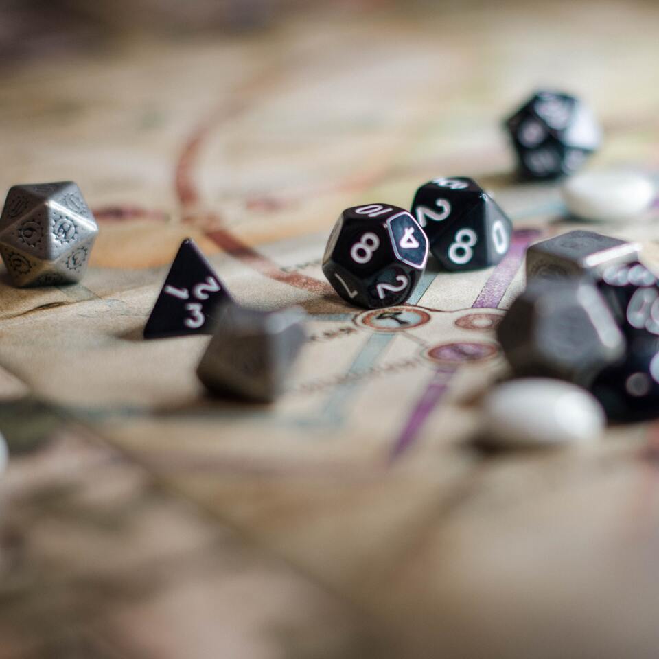 Un puñado de dados de rol de color negro y metálico sobre un mapa.